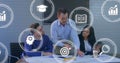 Image of multiple digital icons against diverse colleagues discussing over a plan at office