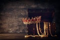 Image of mysterious opened old wooden treasure chest with light and queen/king crown with red Rubies stones. fantasy medieval peri Royalty Free Stock Photo