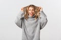 Image of nervous blond woman in panic, ripping hair on head and screaming alarmed, standing distressed against white