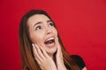 Image of neurotic woman 20s in black t-shirt screaming and looking up with fright, isolated over red background Royalty Free Stock Photo