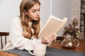 Image of nice caucasian woman reading book and drinking tea