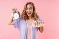 Image of nice happy woman holding alarm and cake while smiling