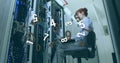 Image of numbers changing and processing over woman using laptop checking computer server