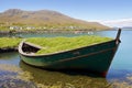 Old, sunken boat at the side of the quay in Kylesalia, Connemara, Ireland, surrounded by green seaweed on a