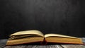 Image of an open antique book on a wooden table against a dark background. Royalty Free Stock Photo