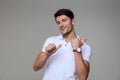 Image of optimistic brunette man wearing basic t-shirt smiling and pointing fingers aside