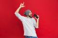 Image of optimistic man 30s singing while listening to music with earphones and mobile phone, isolated over red background Royalty Free Stock Photo