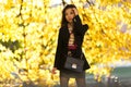 Image of oriental girl with flour, in black coat in autumn forest