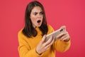 Image of outraged brunette girl playing video game on cellphone