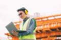 Image outside the industrial construction engineers in yellow protective ear muff discuss new project while using laptop Royalty Free Stock Photo