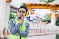 Image outside the industrial construction engineers in yellow protective ear muff discuss new project while using walkie talkie Royalty Free Stock Photo