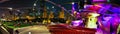 Panorama of outdoor theater in Chicago at night that shows the skyline and the auditorium lit up in purple and yellow