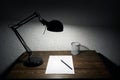 Image of paper sheet on table in light of table lamp. Late night work concept image. Working at home concept image