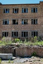 An image of part of an abandoned red brick factory building with broken glass