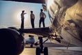 Image of part of aircraft standing in the airport with flight staff