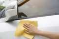 This image is a picture of wiping the car with a yellow microfiber cloth by hands. Royalty Free Stock Photo