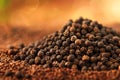 A pile of black peppercorns sits on a bed of ground pepper. Royalty Free Stock Photo