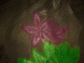 Image of a pink flower with green leaves on a brown background on a fabric texture Royalty Free Stock Photo