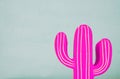 Image of pink neon cactus decoration infront of wooden blue background.