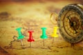 Image of pins attached to map, showing location or travel destination over old map next to vintage compass. selective focus. Royalty Free Stock Photo