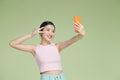 Image of pleased asian woman laughing and showing peace sign while taking selfie photo on cellphone Royalty Free Stock Photo