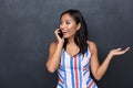 Image of pleased asian woman 30s talking on black cell phone standing isolated Royalty Free Stock Photo