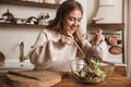 Image of pleased cute woman smiling and making salad