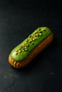 A single Ã©clair on a dark surface, topped with smooth green pistachio glaze. Royalty Free Stock Photo