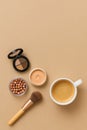 Makeup items arranged on a beige surface next to a cup of coffee vertical flat lay Royalty Free Stock Photo