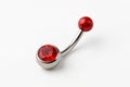 Curved metallic body piercing jewelry featuring a red gemstone set in the larger end. Royalty Free Stock Photo