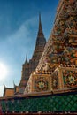 The image portrays ornate temple spires in Thailand, embellished with colorful tiles and patterns, aglow in the warm light of the