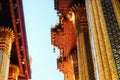 The image portrays a temple in Thailand, adorned with intricate gold and red patterns. Small statues embellish the roof. The photo