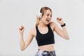 Image of positive blond woman 20s dressed in sportswear listening to music with headphones during workout in gym