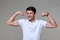 Image of positive brunette man smiling and showing his biceps