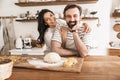 Image of positive family making homemade pasta of dough while cooking together in kitchen at home