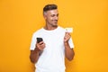 Image of positive guy 30s in white t-shirt holding mobile phone and credit card Royalty Free Stock Photo