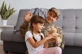 Image of positive optimistic young adult soldier man wearing camouflage uniform returning home after army, spending time with