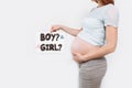 Image of a pregnant woman holding a paper near the pregnant belly, with a boy or girl issues Royalty Free Stock Photo