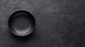 A black bowl with a speckled texture sits on a dark gray surface. Royalty Free Stock Photo