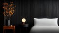 A modern bedroom with a black wood paneled wall, white bed, and wooden nightstand. Royalty Free Stock Photo