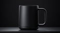 A black mug with a handle and a base sits on a black surface. Royalty Free Stock Photo