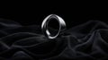 A silver ring with a twisted design sits on a black fabric. Royalty Free Stock Photo