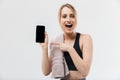 Image of pretty blond woman 20s dressed in sportswear with towel over neck using smartphone during workout in gym Royalty Free Stock Photo