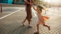 Image of a pretty little girl dancing together with her mother in sunlight outside. Cute daughter playing outdoor with her mom.