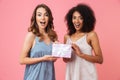 Pretty shocked young two women holding gift present box.