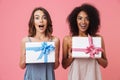 Pretty shocked young two women holding gifts