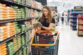 Image of pretty woman with cart choosing products in supermarket