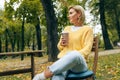 Image of pretty young woman drinking coffee at terrace cafetaria in the park. Female in the city street drinking hot cappuccino,