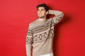 Image of puzzled and indecisive man in christmas sweater, looking at upper left corner, thinking about new year holidays