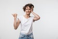 Image of puzzled woman with short hair in basic t-shirt grabbing her head and pointing finger aside at copyspace